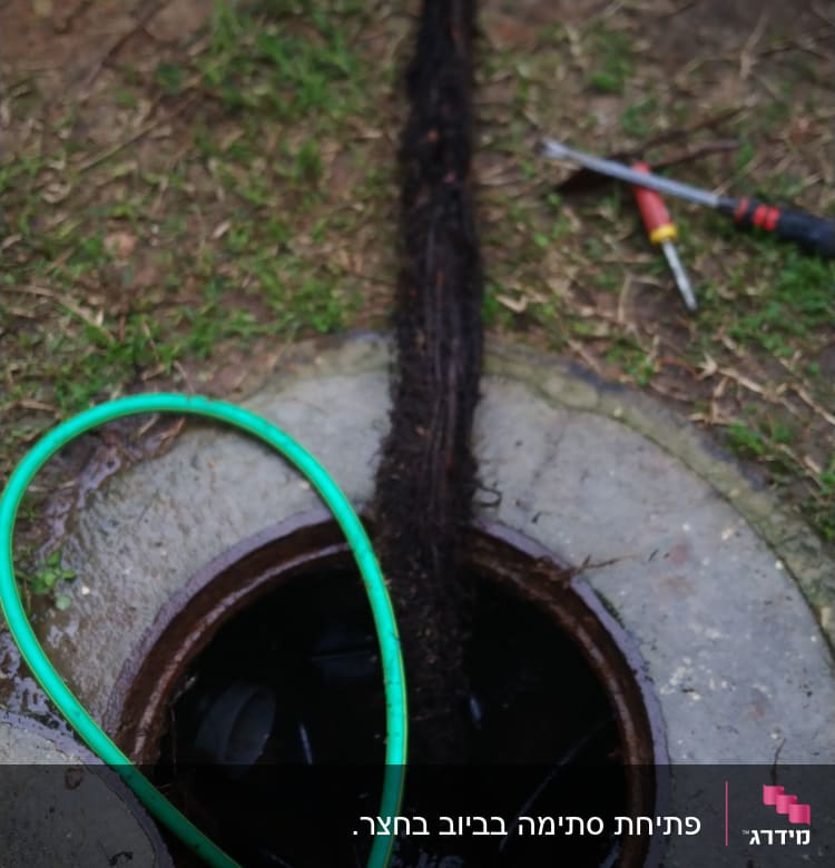 צינור ירוק וכלי עבודה ליד פתח ביוב